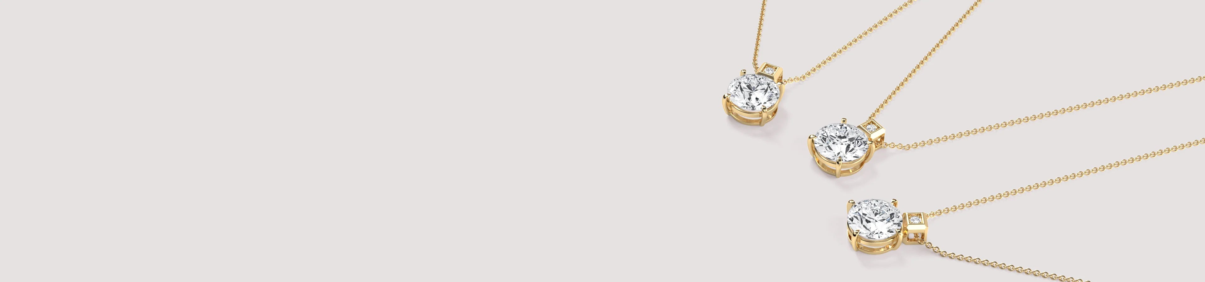Three gold necklaces with diamond pendants on a light gray background